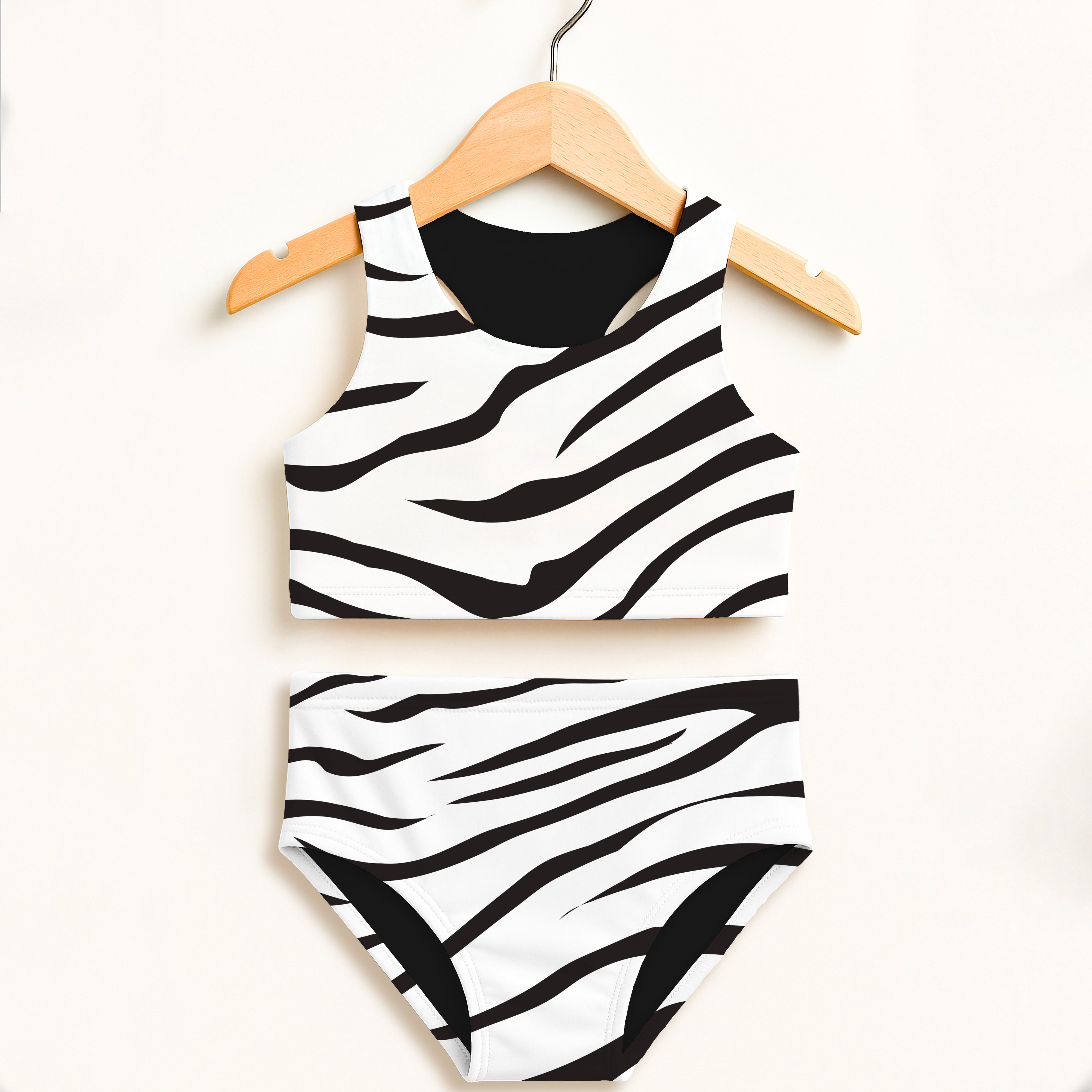 Girls zebra print two-piece swimsuit with black and white stripes hanging on wooden hanger featuring UPF 50+ protection